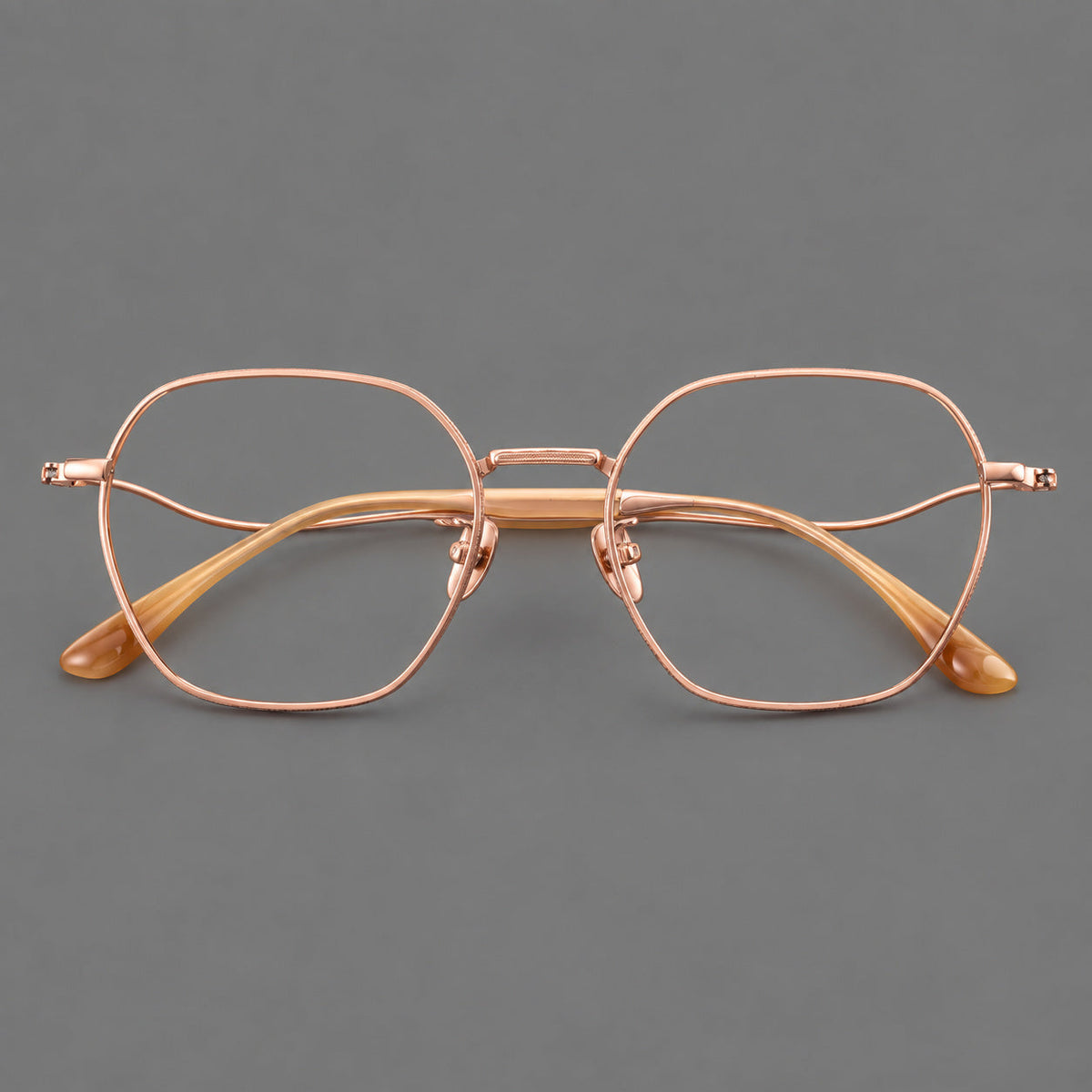 Geometric titanium glasses with engraved rim edges and curved temple joins in Rose Gold, front view