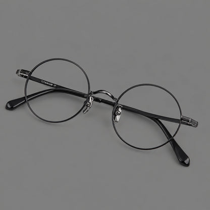 Compact circular titanium glasses with a curved bridge and wavy engraved temples in Black, three quarter view