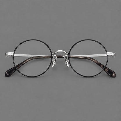 Compact circular titanium glasses with a curved bridge and wavy engraved temples in Black and Silver, front view frame detail
