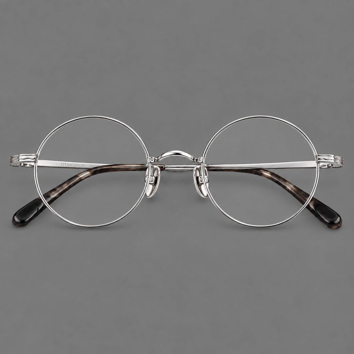 Compact circular titanium glasses with a curved bridge and wavy engraved temples in Silver, front view