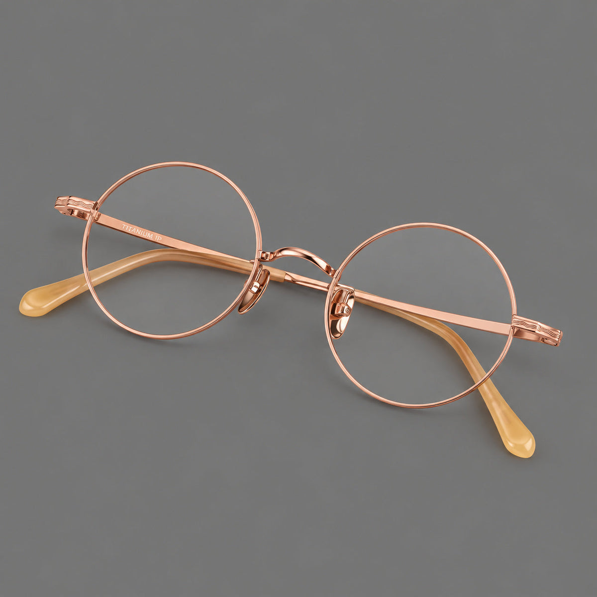 Compact circular titanium glasses with a curved bridge and wavy engraved temples in Rose Gold, three quarter view