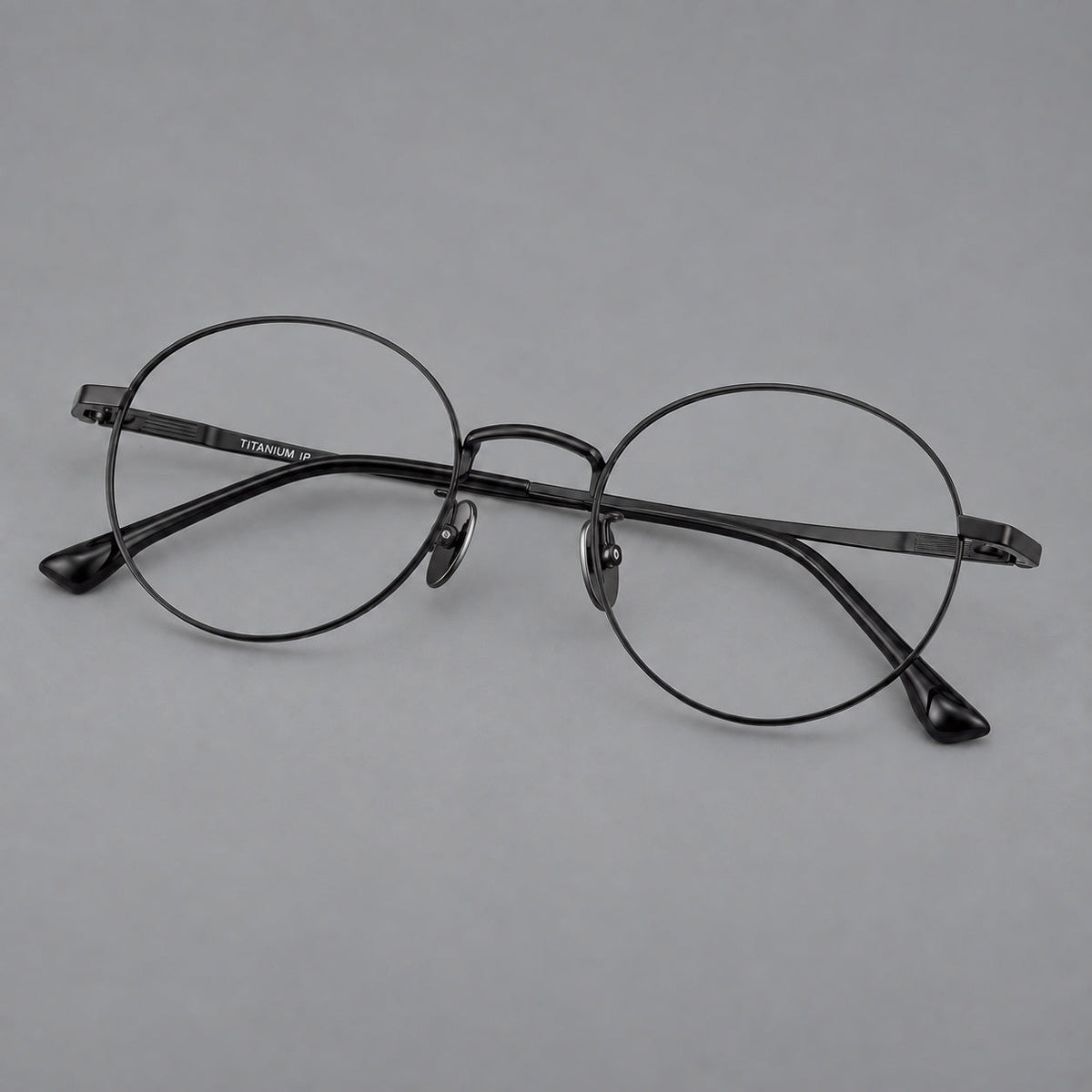 Classic circular titanium glasses with a raised bridge and lined temple accents in Black, three quarter view