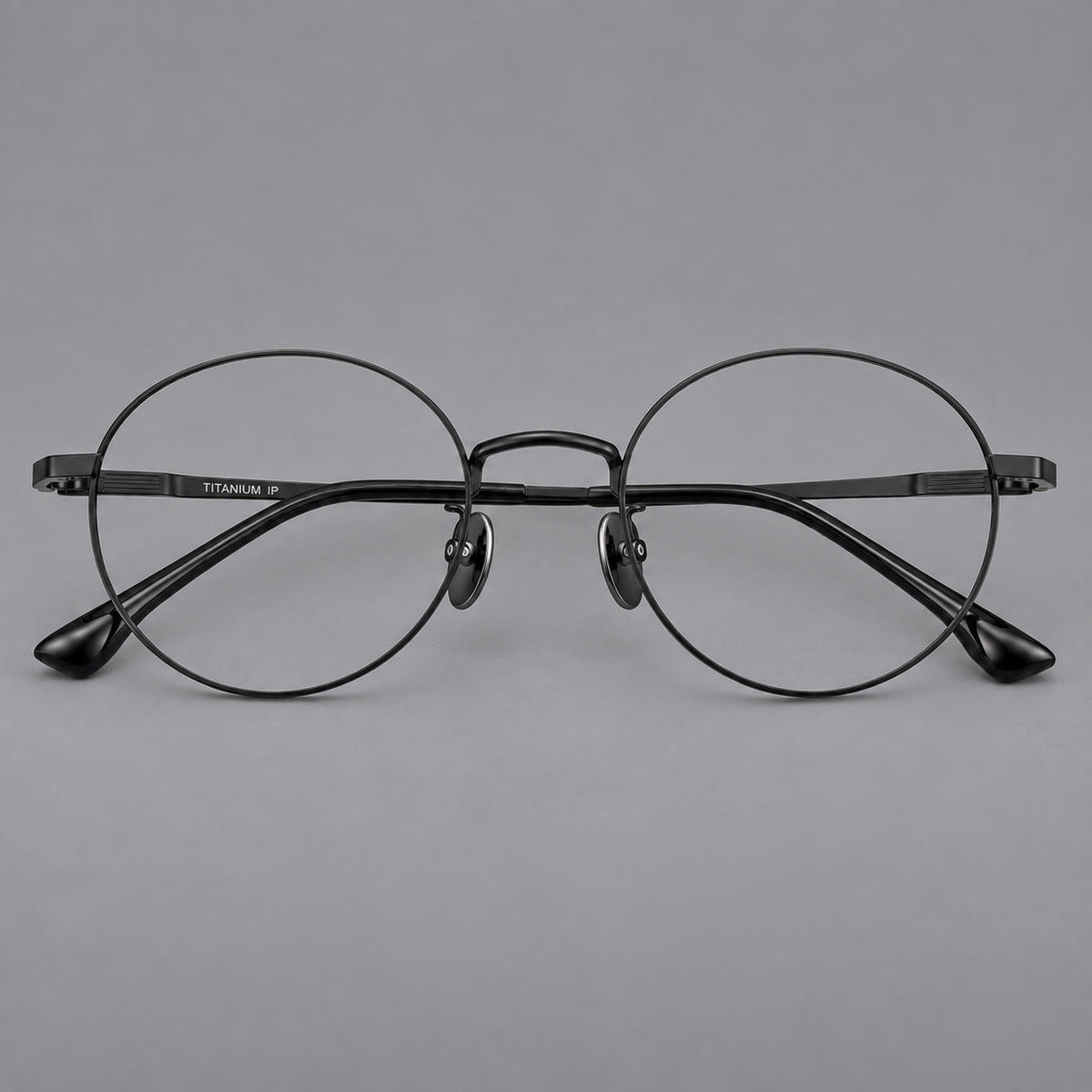 Classic circular titanium glasses with a raised bridge and lined temple accents in Black, front view