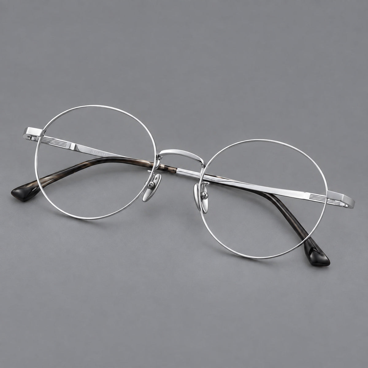Classic circular titanium glasses with a raised bridge and lined temple accents in Silver, three quarter view