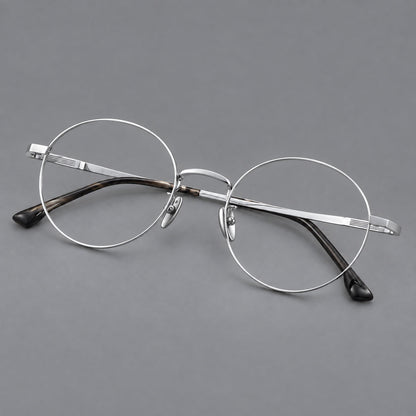 Classic circular titanium glasses with a raised bridge and lined temple accents in Silver, three quarter view lens detail