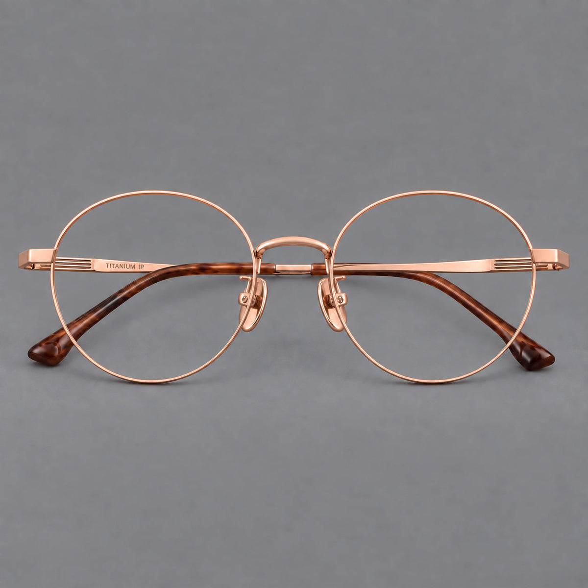 Classic circular titanium glasses with a raised bridge and lined temple accents in Rose Gold, front view