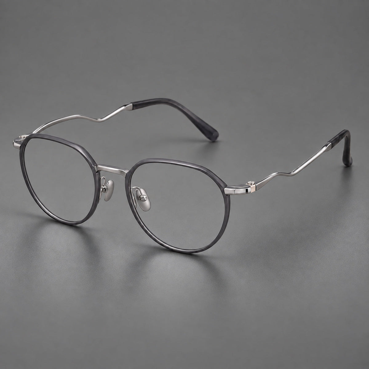 Rounded titanium glasses with a short bridge and distinctive wavy metal temples in Matte Gray and Silver, three quarter view