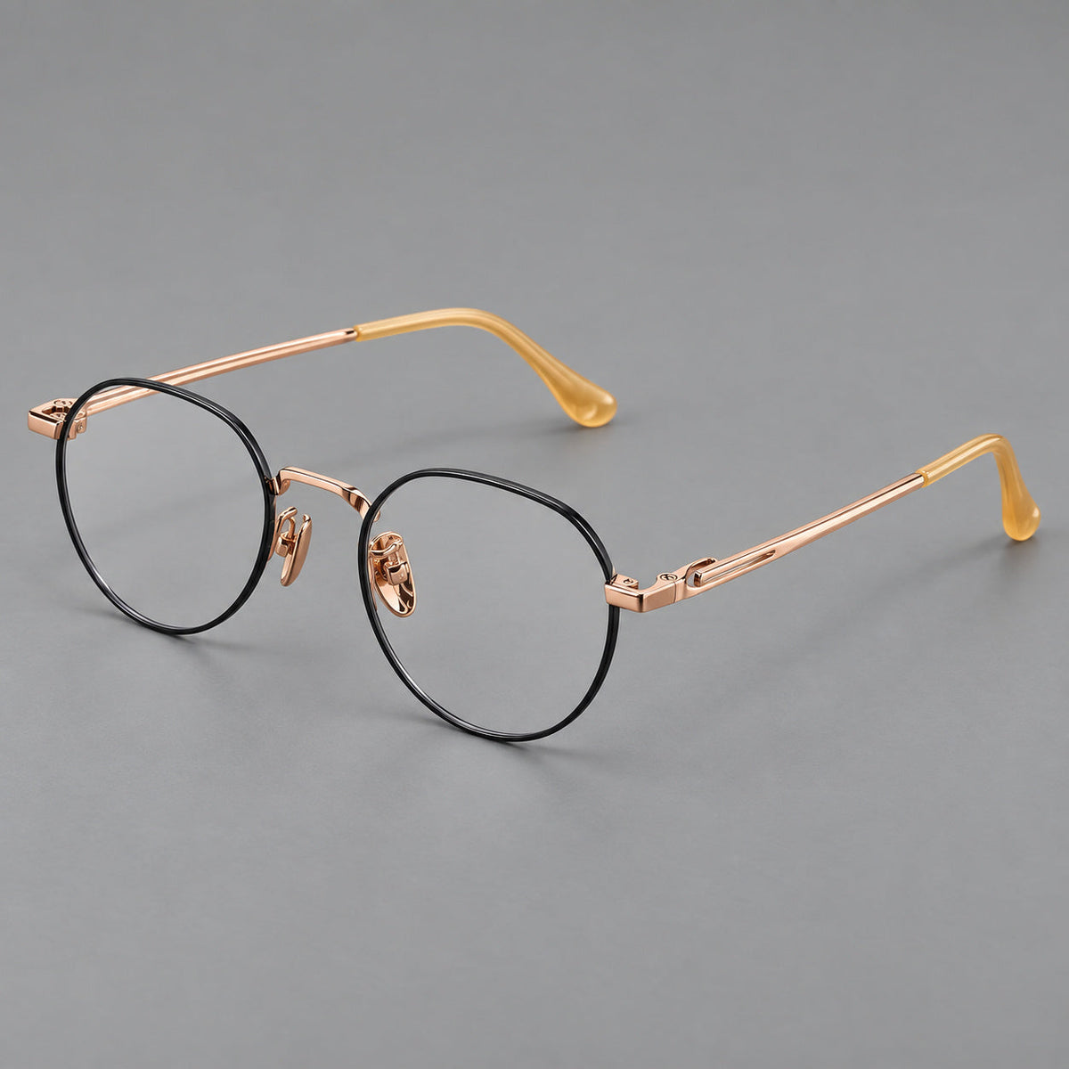 Small panto titanium glasses with an angular bridge and recessed temple details in Black and Rose Gold, three quarter view