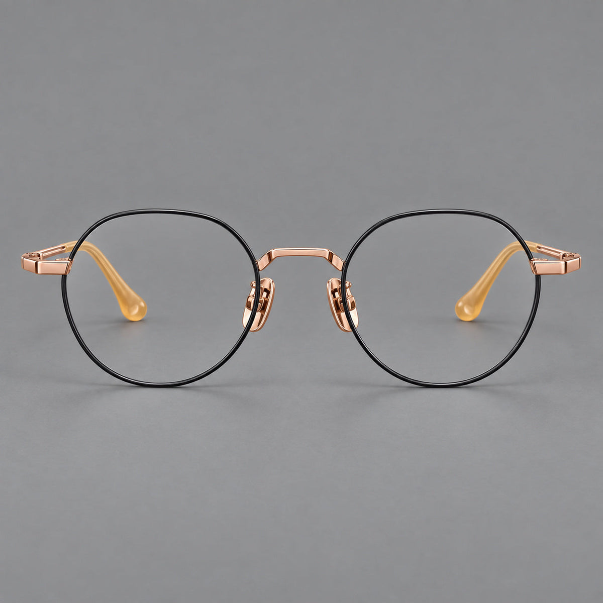 Small panto titanium glasses with an angular bridge and recessed temple details in Black and Rose Gold, front view