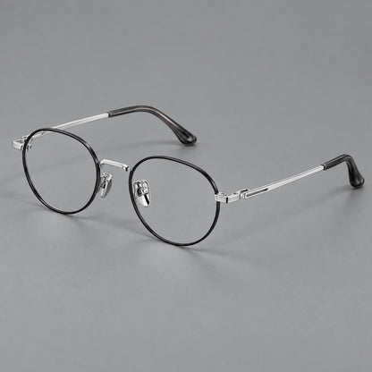 Small panto titanium glasses with an angular bridge and recessed temple details in Black and Silver, three quarter view lens detail