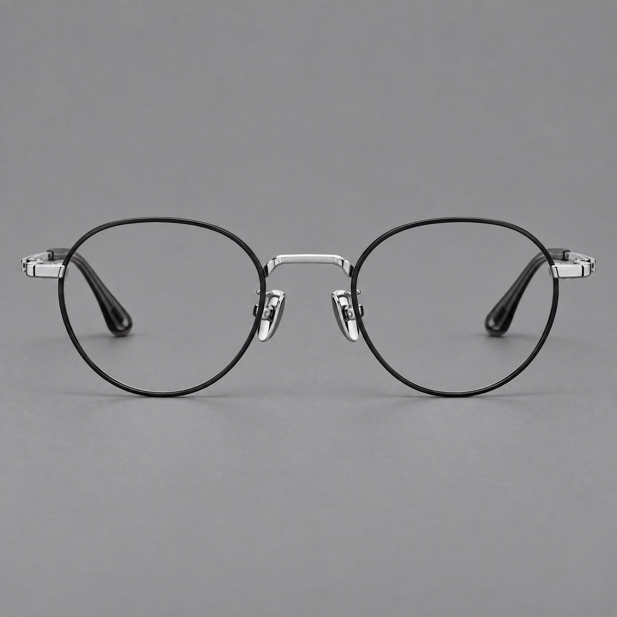 Small panto titanium glasses with an angular bridge and recessed temple details in Black and Silver, front view