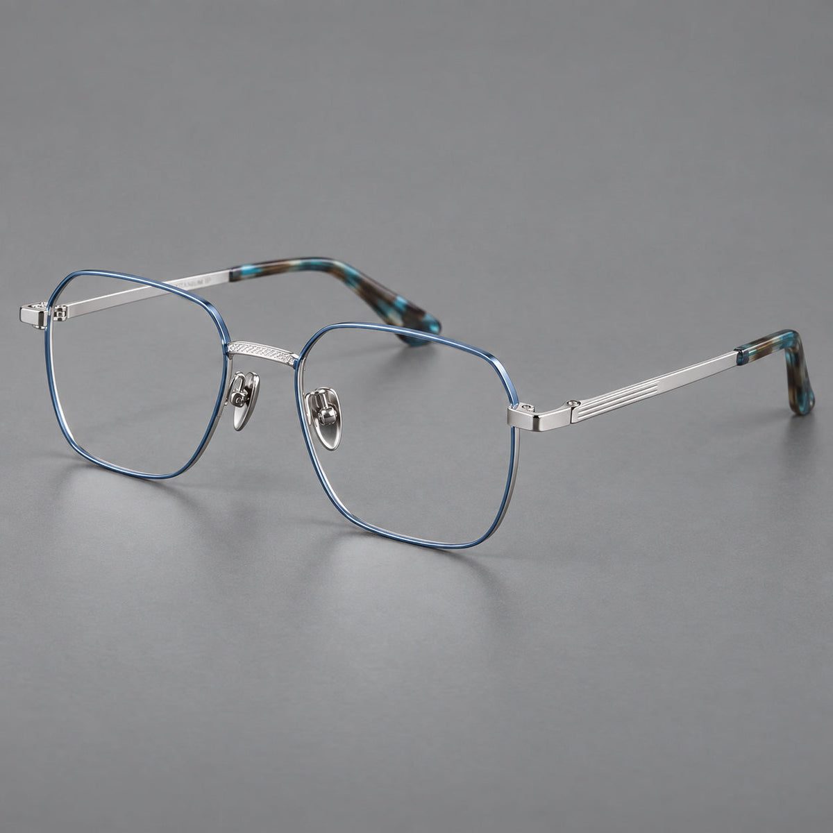 Geometric square titanium glasses with a textured bridge and fine temple grooves in Blue and Silver, three quarter view