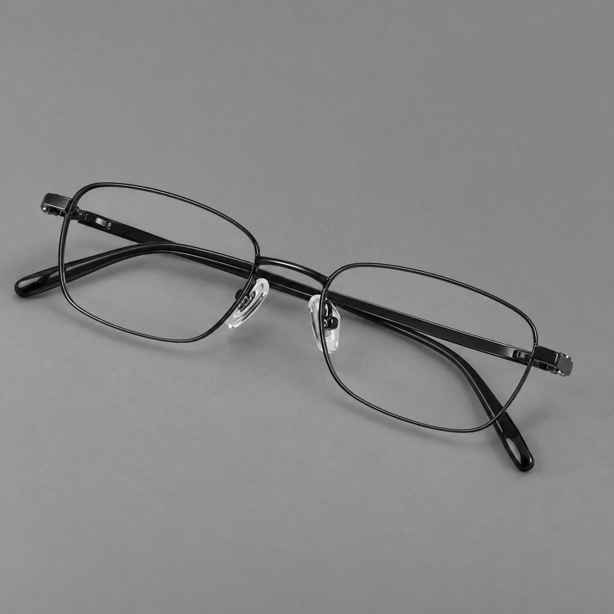 Shallow rectangular titanium glasses with a broad bridge and stepped temple joins in Black, three quarter view