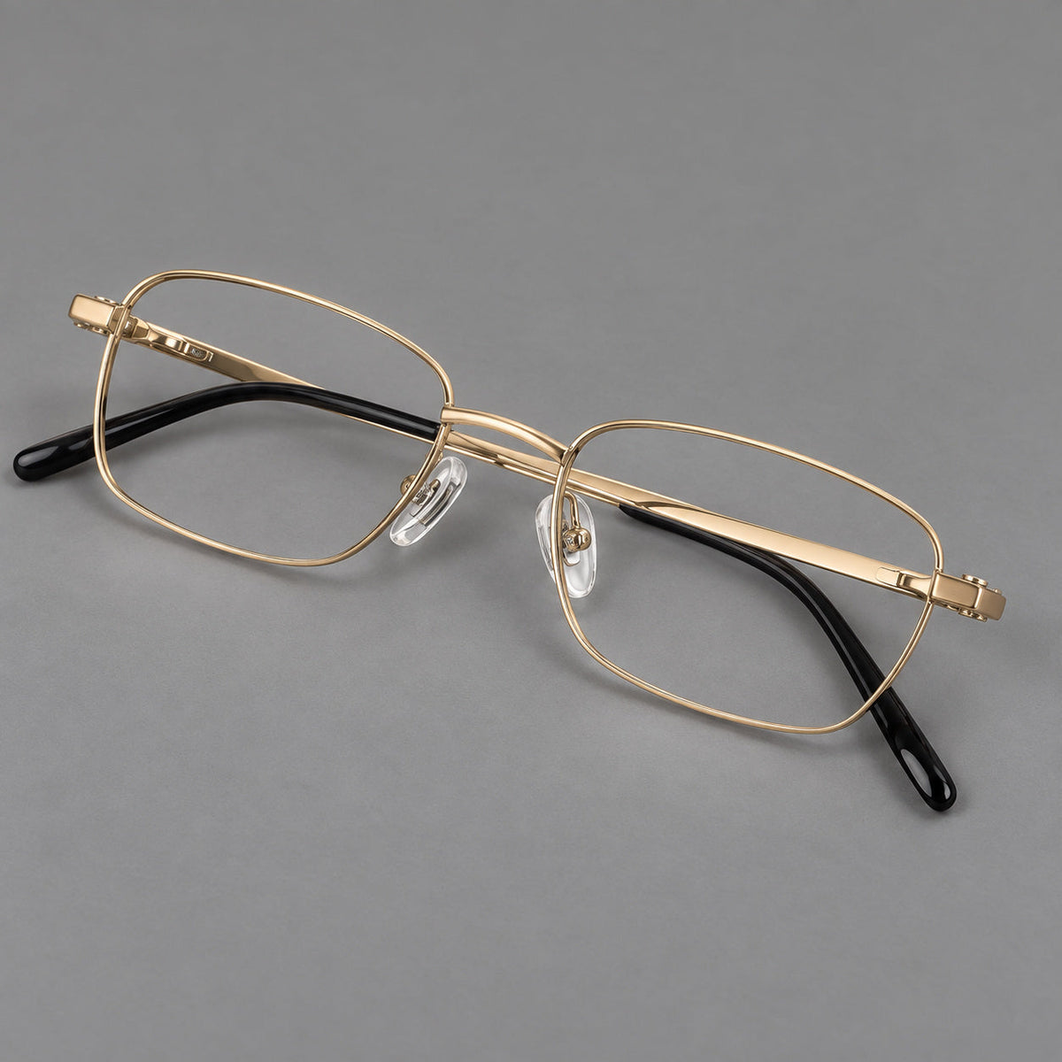 Shallow rectangular titanium glasses with a broad bridge and stepped temple joins in Gold, three quarter view
